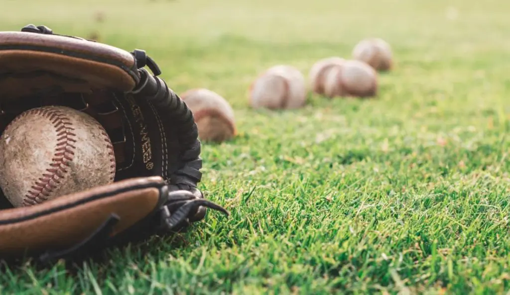 Photo of a baseball mitt and balls, illustrating a love story involving a baseball player.