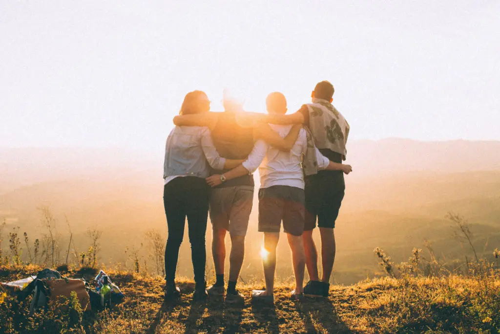Group of older friends embrace at sunset