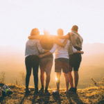 Group of older friends embrace at sunset