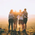 Group of older friends embrace at sunset