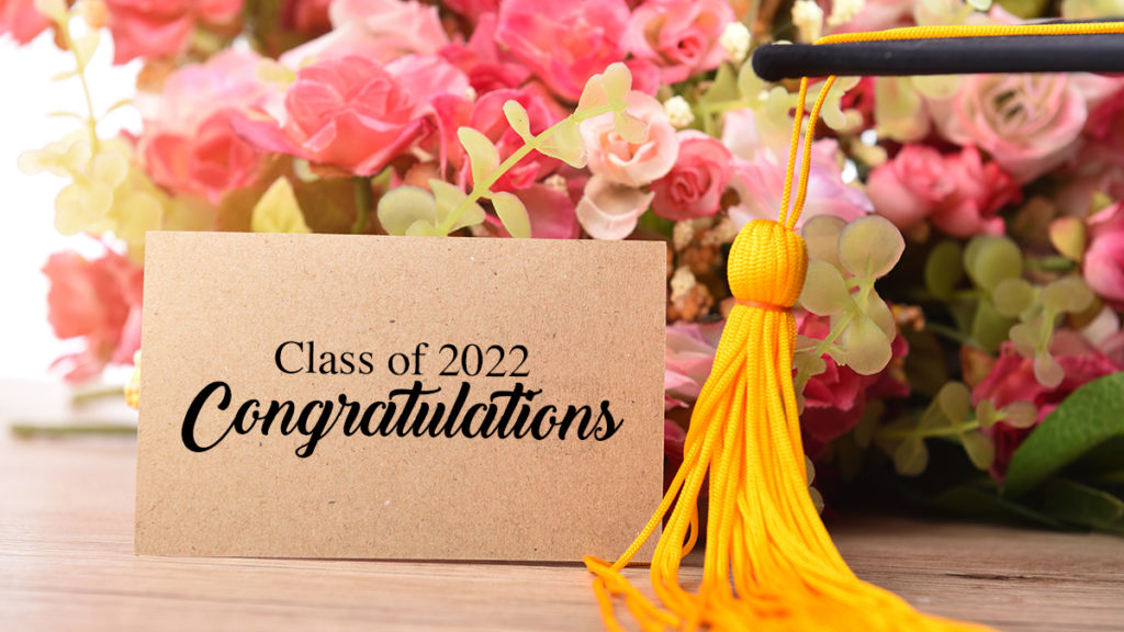 a photo of graduation messages with a card, flowers, and tassel