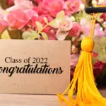 a photo of graduation messages with a card, flowers, and tassel
