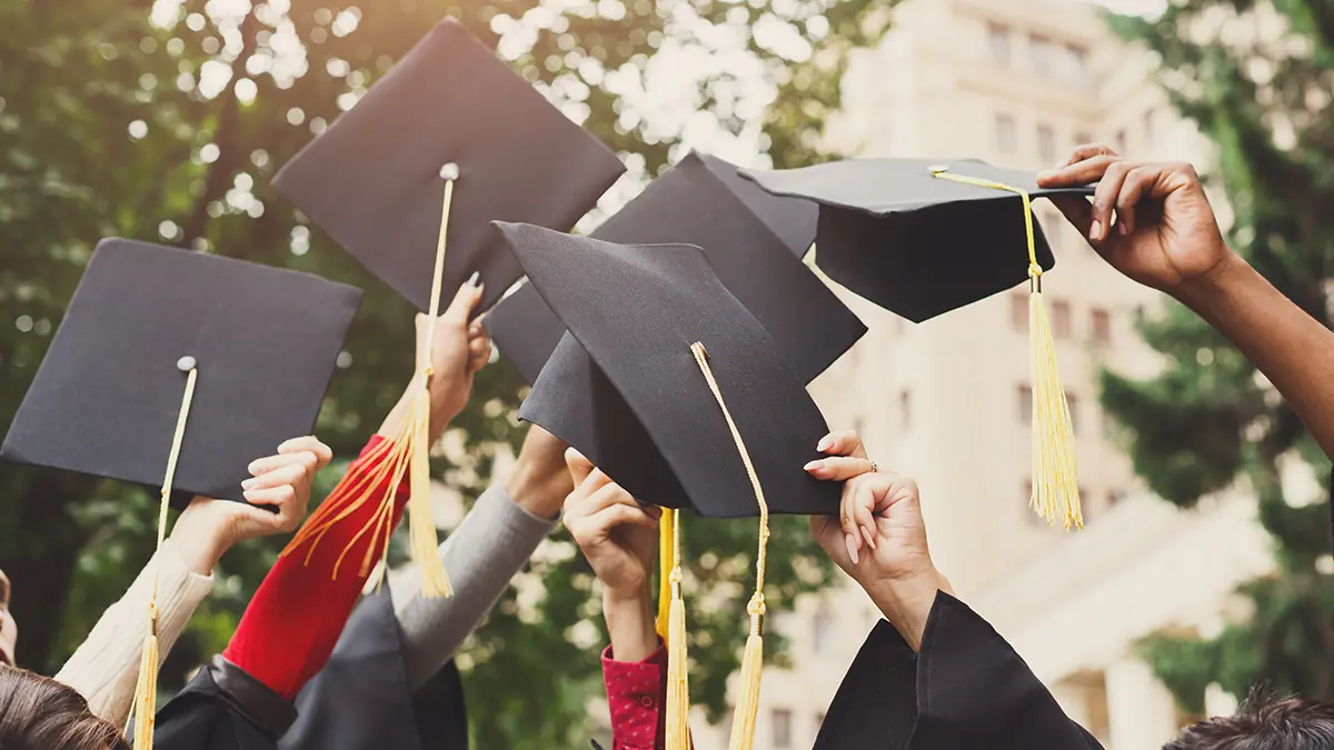 A photo of graduation messages with graduates raising their caps in the air