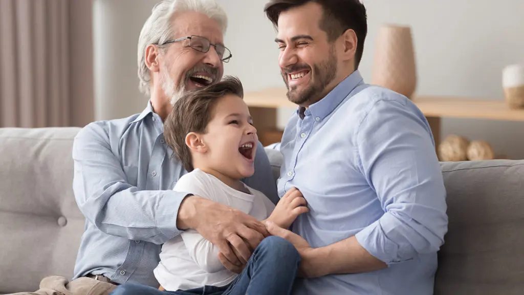 Father's day ideas with a grandfather, son and grandson sitting on a couch and laughing