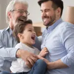 Father's day ideas with a grandfather, son and grandson sitting on a couch and laughing