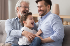 Father's day ideas with a grandfather, son and grandson sitting on a couch and laughing