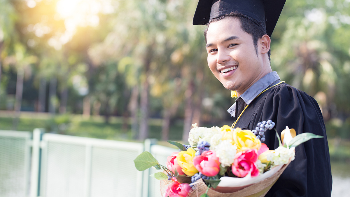 A photo of flowers for graduation with a male college graduate with flowers