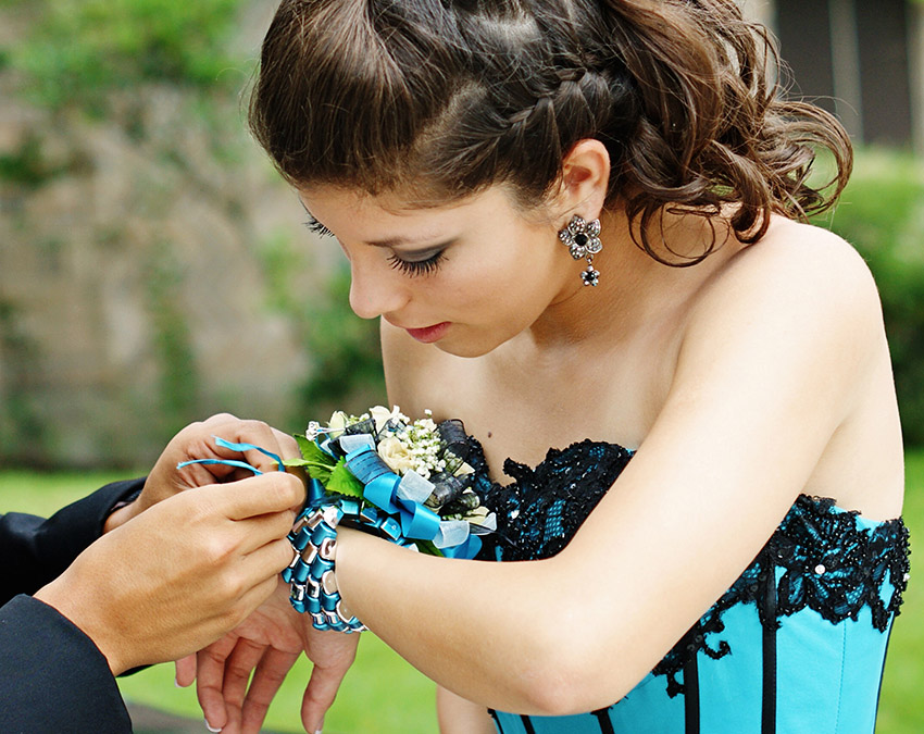 a photo of prom corsage with man tying a wrist corsage