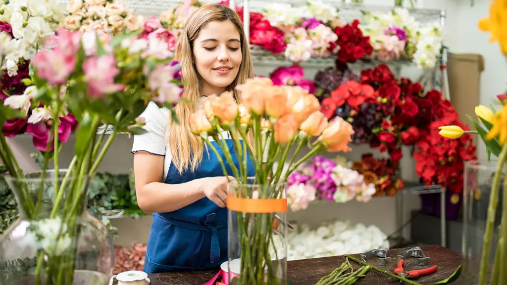 a photo of rose care with woman arranging roses in a vase