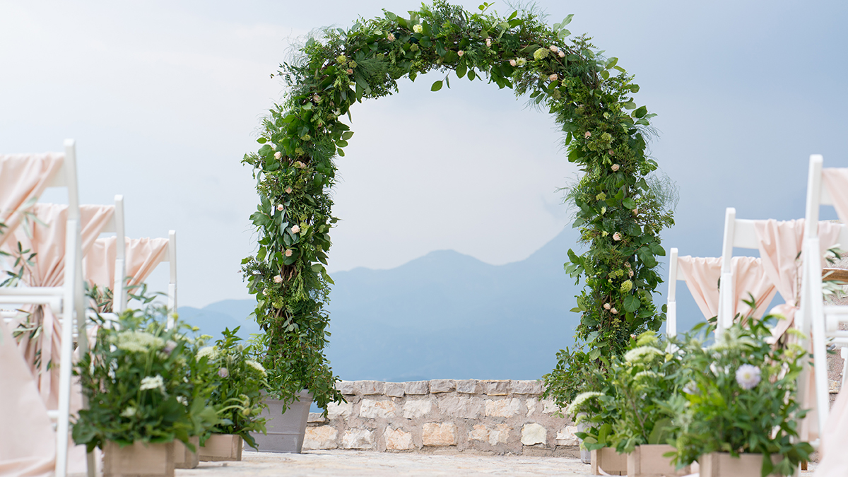 A photo of summer wedding flowers with a large botanical archway