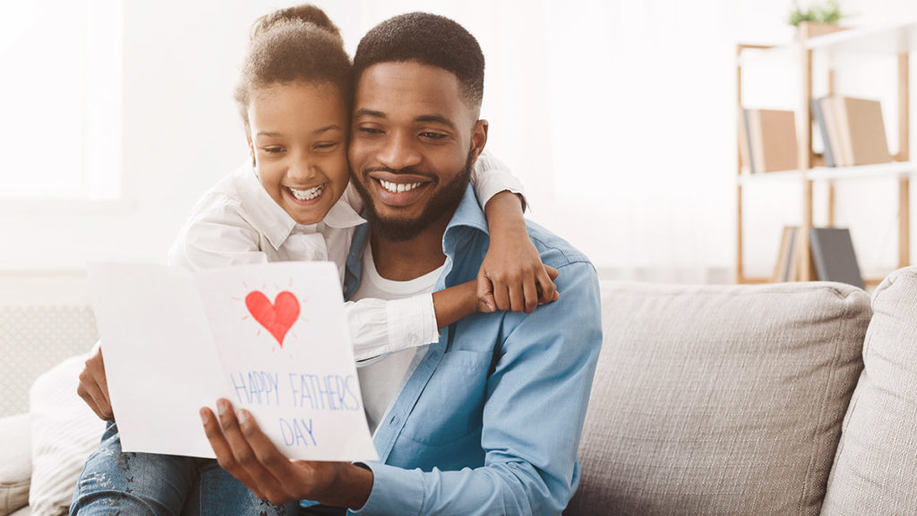 Una foto de ideas para el día del padre con una hija dándole a papá una tarjeta del día del padre