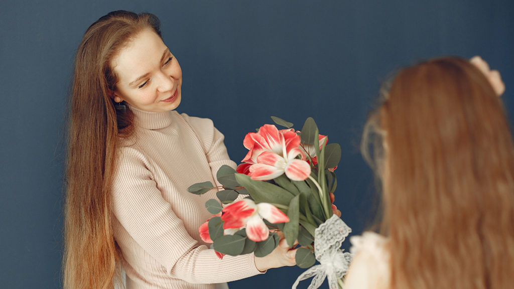 Photo of psychology of giving with a woman receiving a beautiful floral bouquet as a gift. 