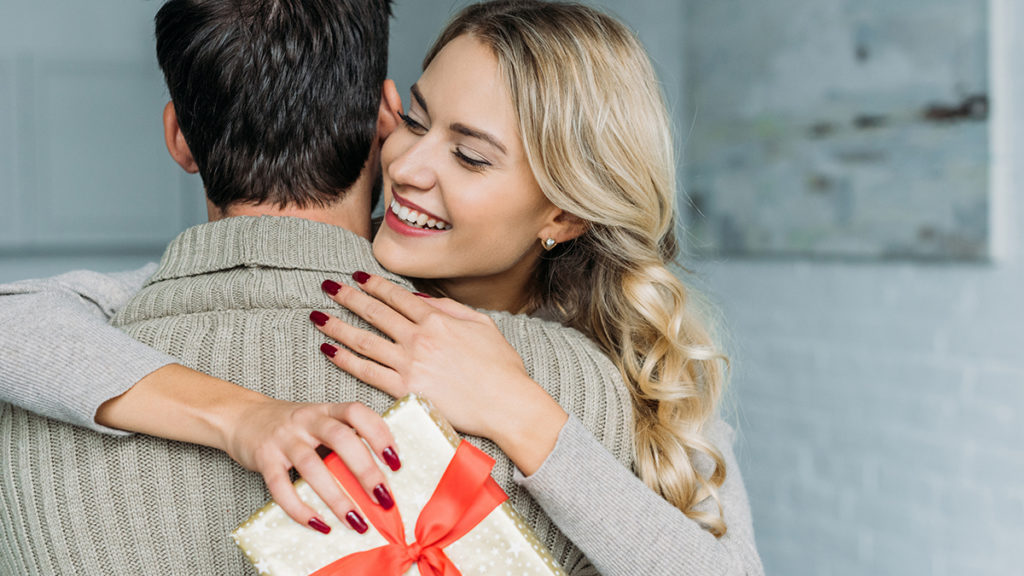 A photo of the psychology of giving with a woman hugging a man who just gave her a gift.