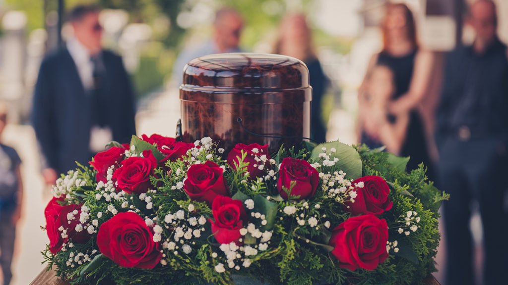a photo of a cremation service with a funerary urn with ashes of dead and flowers at funeral