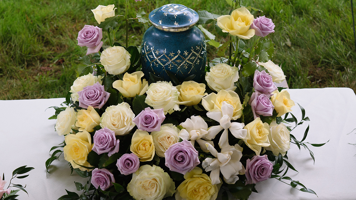a photo of cremation services with funeral flowers around an urn