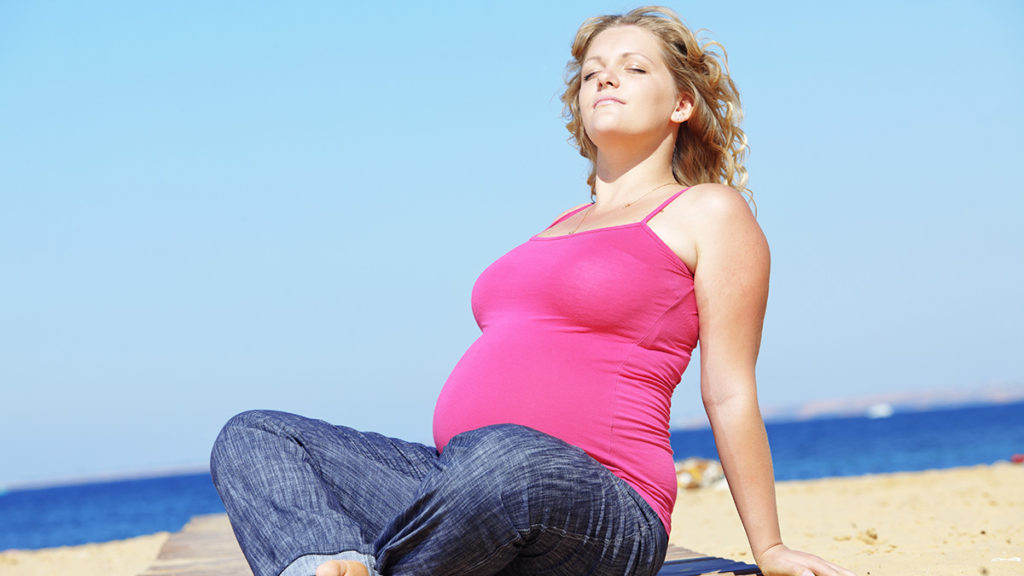 a photo of july birthdays with a pregnant woman sunning herself on the beach