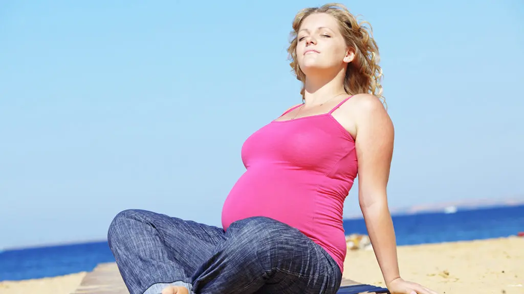 a photo of july birthdays with a pregnant woman sunning herself on the beach