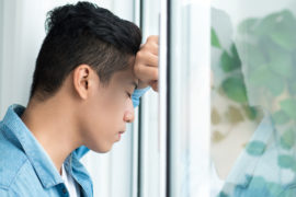 a photo of collective grief with a man leaning on window looking worried