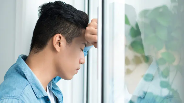 a photo of collective grief with a man leaning on window looking worried