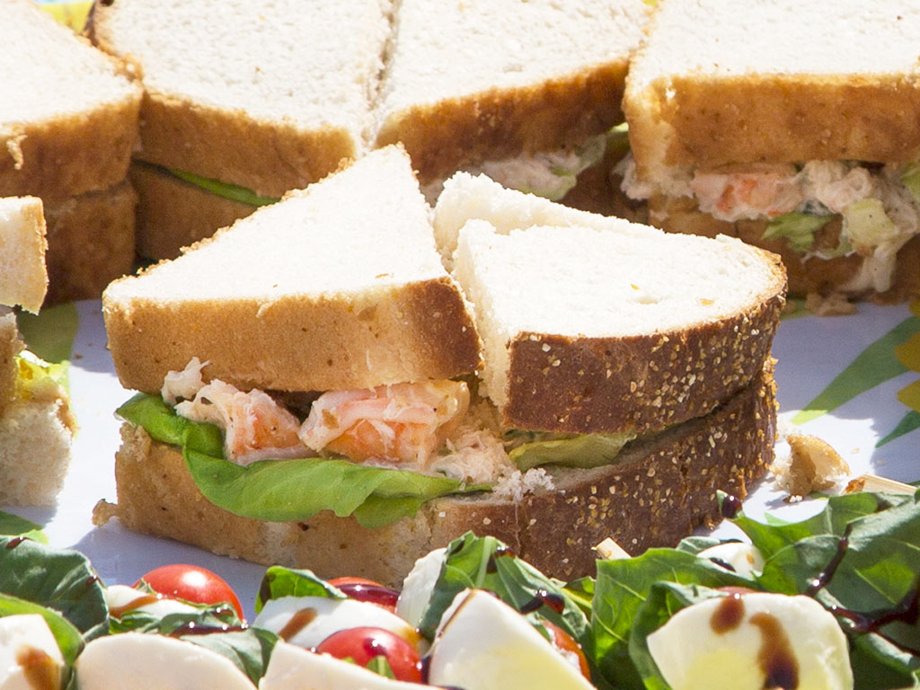 una foto de un picnic en la playa con sándwiches de ensalada de mariscos