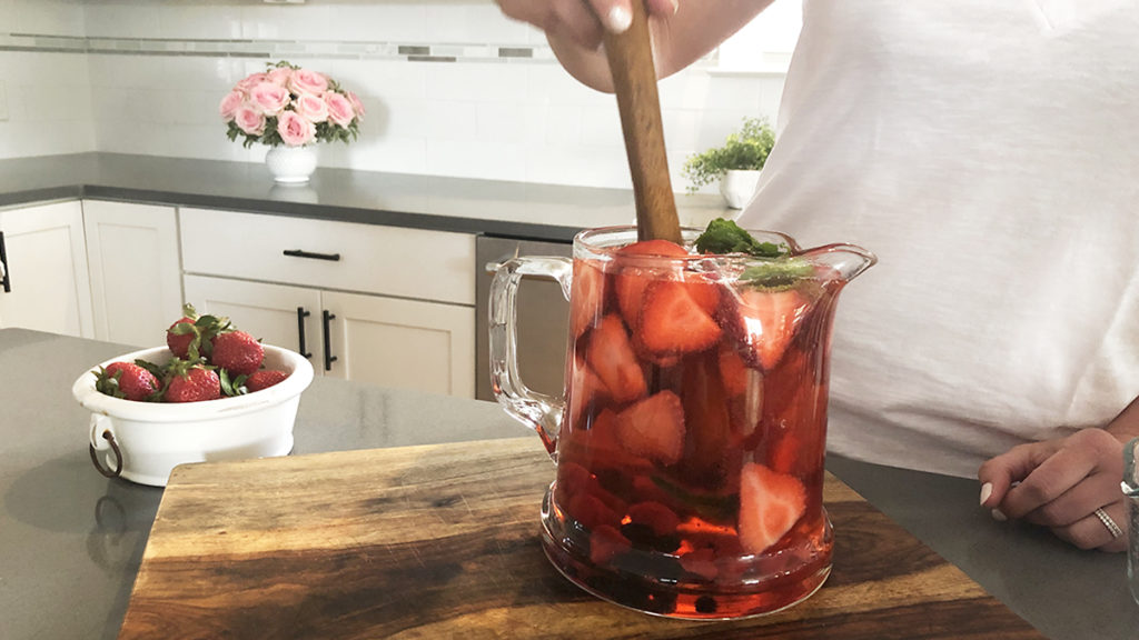 Photo of rosé sangria with stirring the pitcher of fruit and sangria