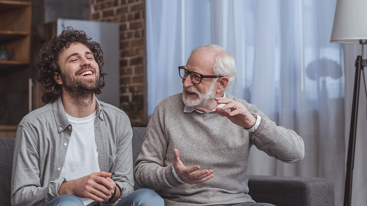 Una foto de un padre bromeando con un anciano que le cuenta un chiste a su hijo