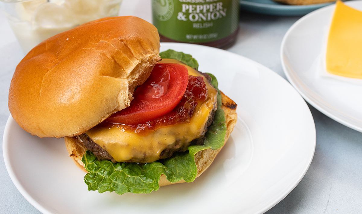 a photo of grill burgers with a cheeseburger on a plate