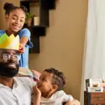 A photo of father's day gift guide with two kids putting a paper crown on their dad's head