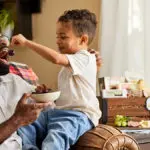 A photo of father's day gift ideas with a boy feeding a man a cherry