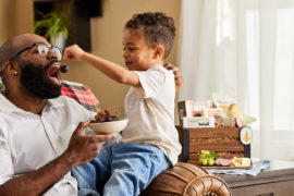 A photo of father's day gift ideas with a boy feeding a man a cherry