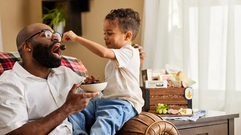 A photo of father's day gift ideas with a boy feeding a man a cherry