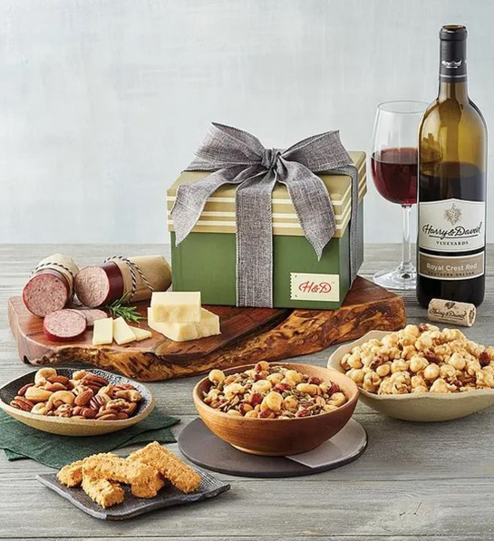 Una foto de ideas de regalos para el Día del Padre que incluye una colección de tazones llenos de bocadillos salados junto a una tabla llena de salami y queso con una botella de vino