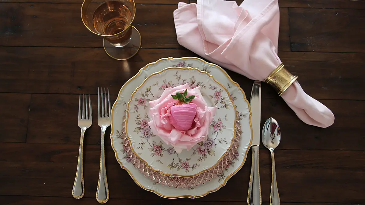 photo of waxed roses with a waxed rose in a table setting with a chocolate covered strawberry sitting on it