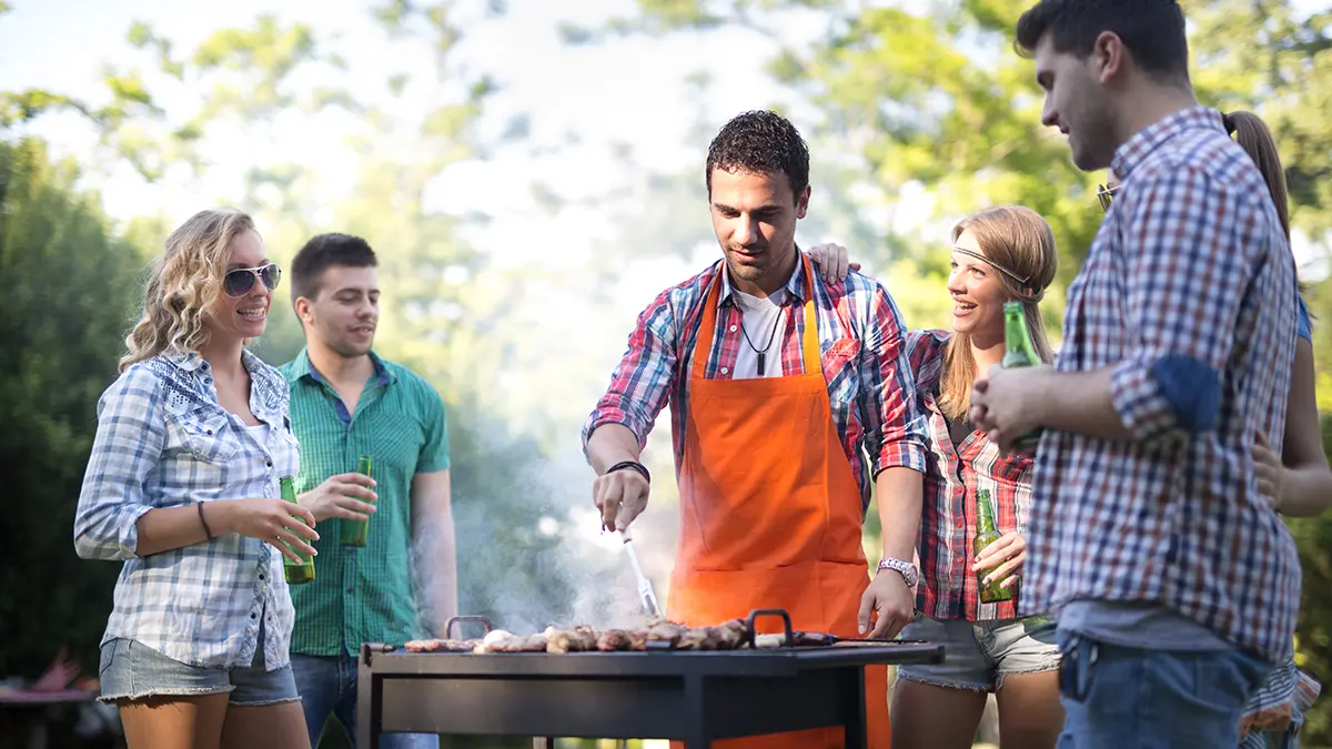 backyard party with young people having barbecue on summer day