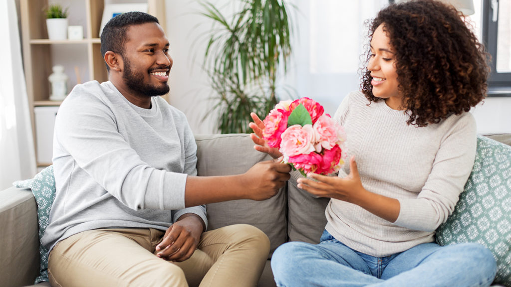 Photo of flowers for a date with african american couple with bunch of flowers at home