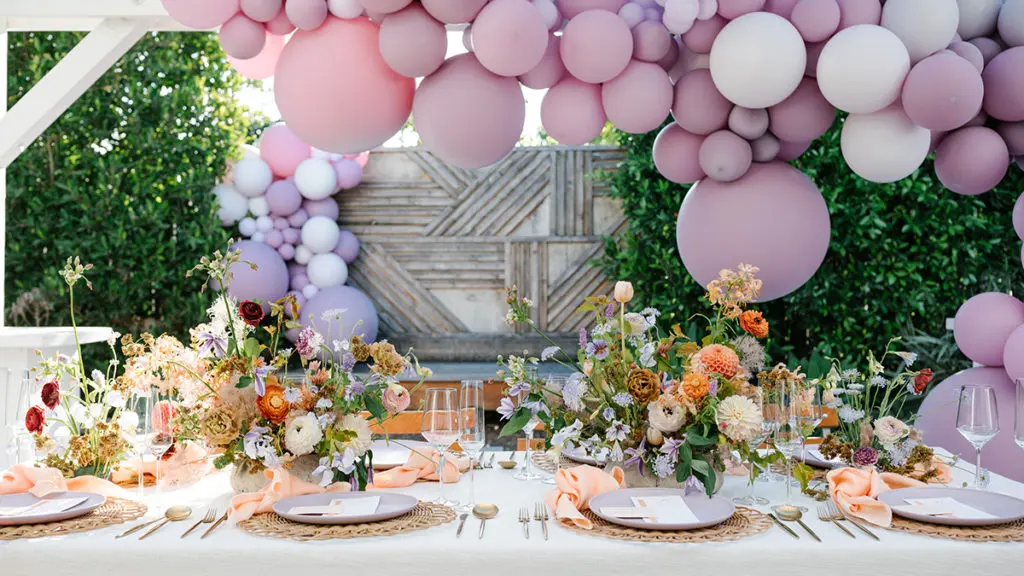 Bridal shower setup with balloon arch over a table full of flowers and set for dinner