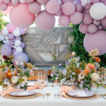 Bridal shower setup with balloon arch over a table full of flowers and set for dinner