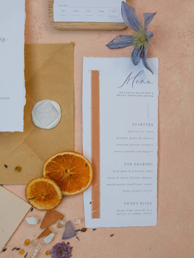 Bridal shower menu on a table surrounded by artisanal paper and dried orange slices.