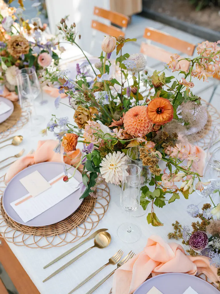 Bridal shower table set with plates and utensils and bouquets of flowers.