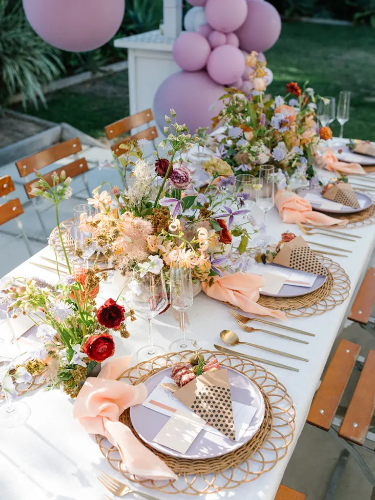 Bridal shower table set with plates and utensils and bouquets of flowers.