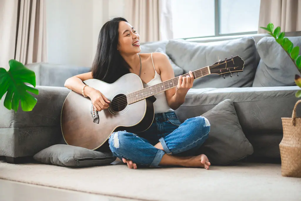 Why hobbies are important: Photo of a woman enjoying her hobby of playing a guitar