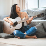 Why hobbies are important: Photo of a woman enjoying her hobby of playing a guitar