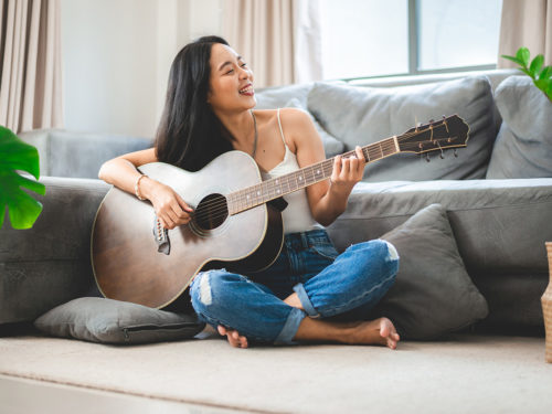 Why hobbies are important: Photo of a woman enjoying her hobby of playing a guitar