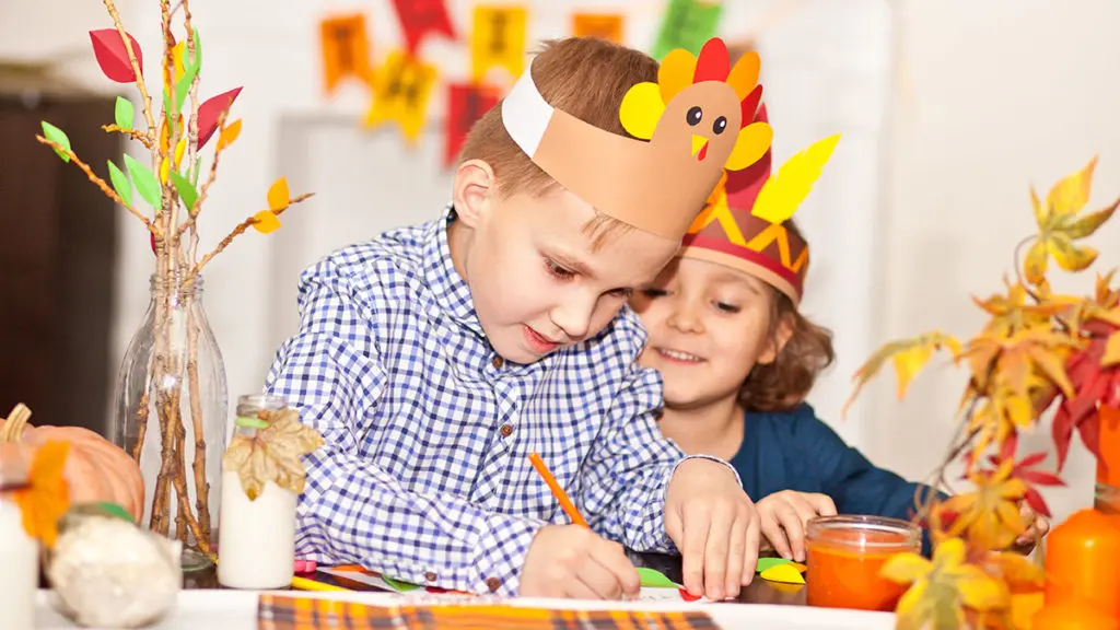 Thanksgiving greetings with boy writing thanksgiving card