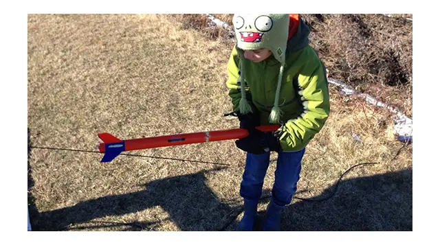 Photo of a boy getting a rocket ready for launch.