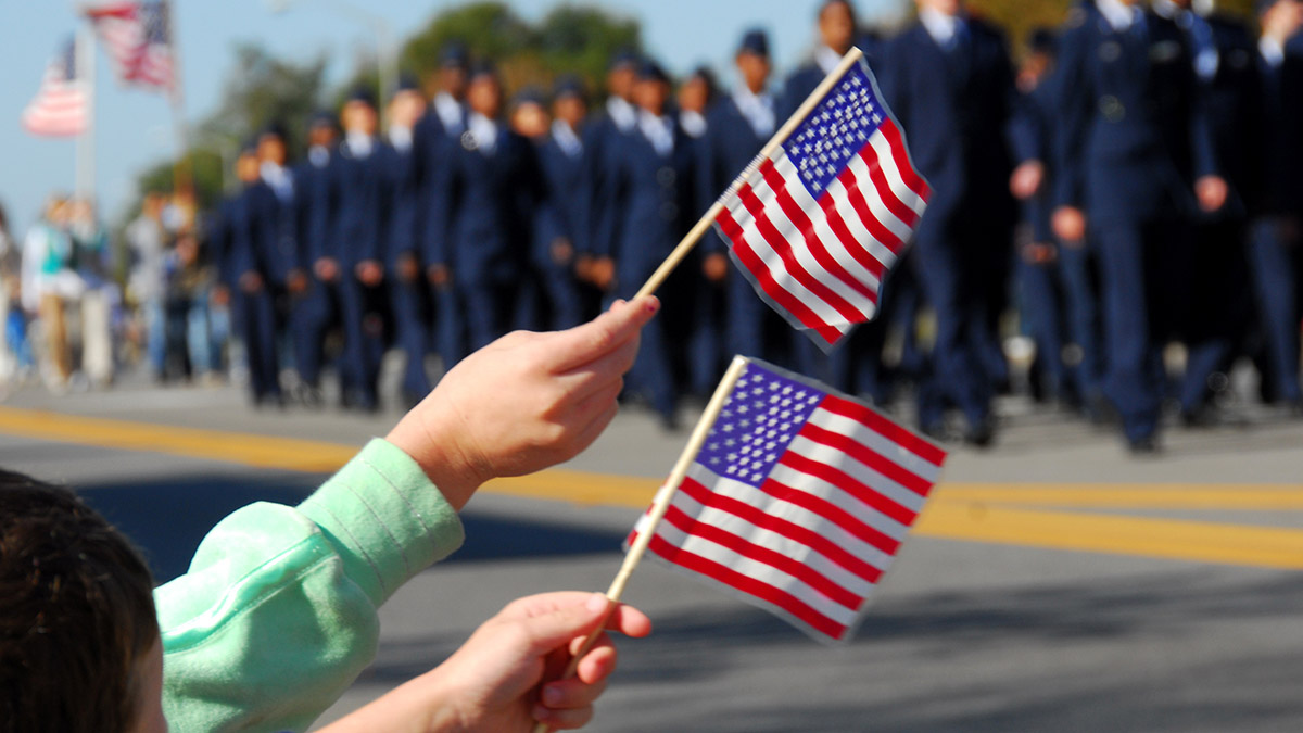 honoring veterans with waving flags at veterans day parade