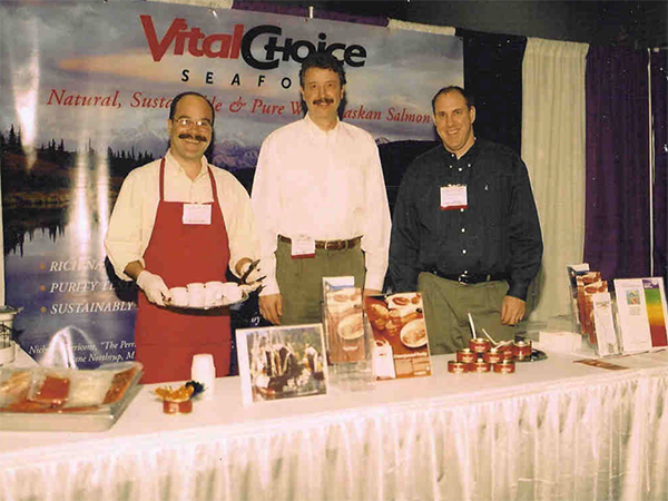 Photo of Vital Choice founders Randy Hartnell and Dave Hamburg at a grocery store sharing stories about their ocean adventures and great seafood.