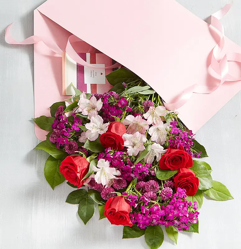 Bouquet of pink roses next to a gift with a happy birthday card