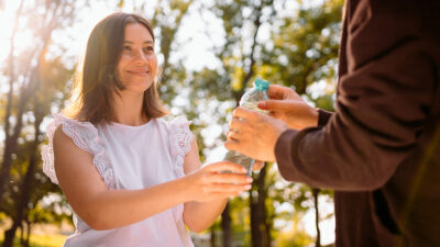 mujer dando agua a personas sin hogar