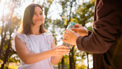 woman giving water to homeless person